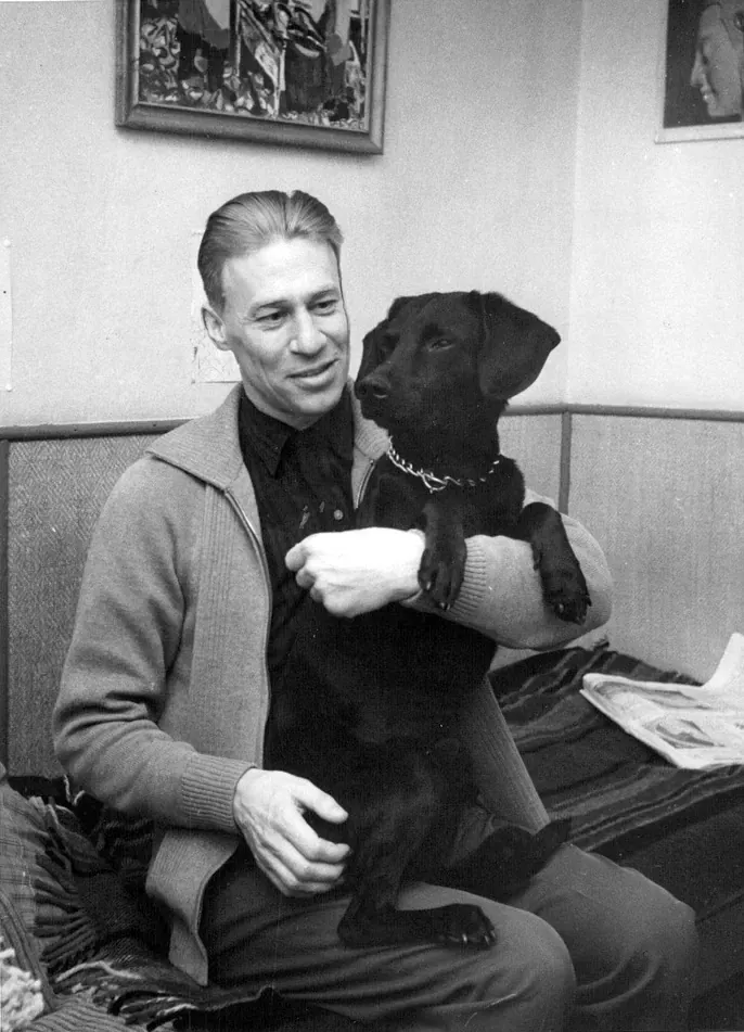Vintage black and white photograph of a man holding a black Labrador retriever